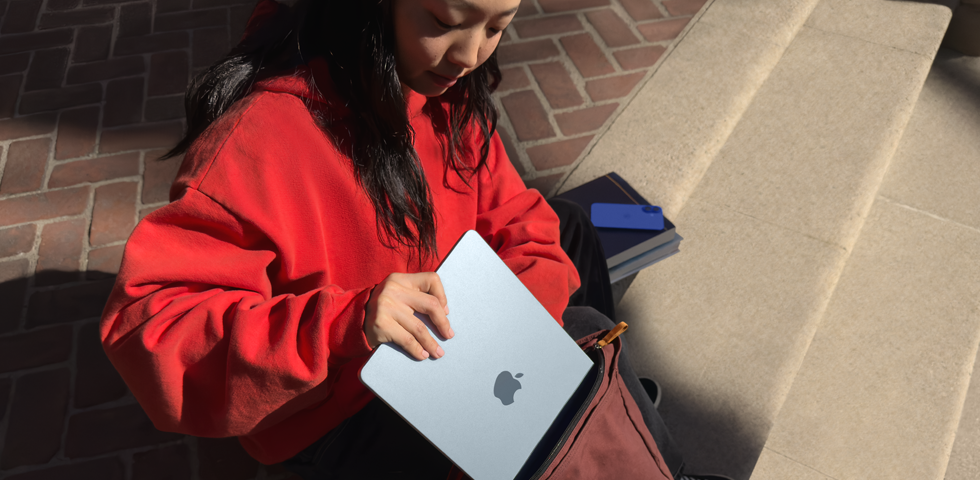 A student placing MacBook Air into their backpack