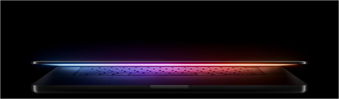 A slightly open MacBook Pro casts a multicoloured glow from the screen onto the keyboard